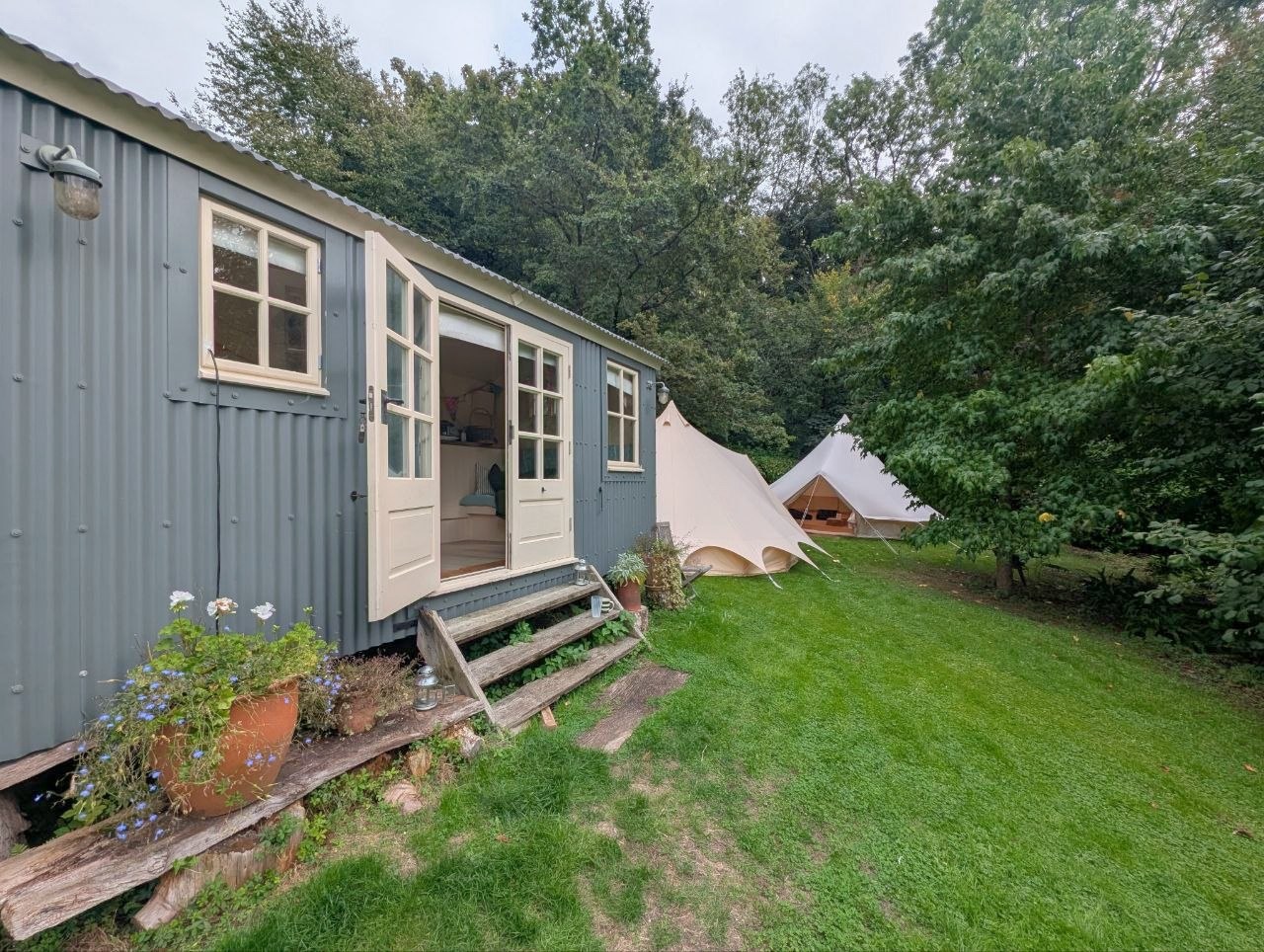 The host’s blue-grey shepherd’s hut beside two Camp Chic garden bell tents
