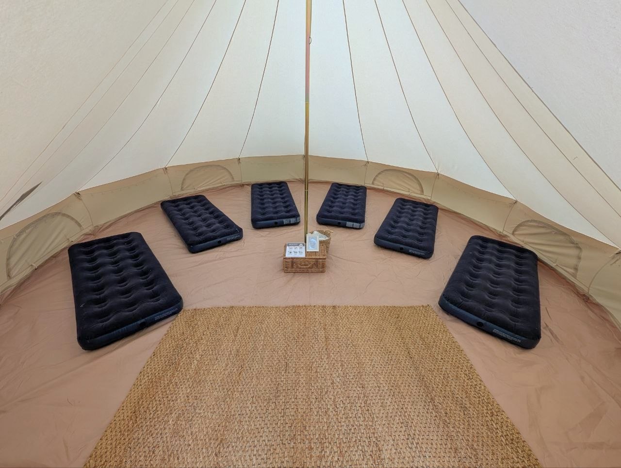 Six airbeds arranged around the inside of a Rustic Bell tent with a large central rug