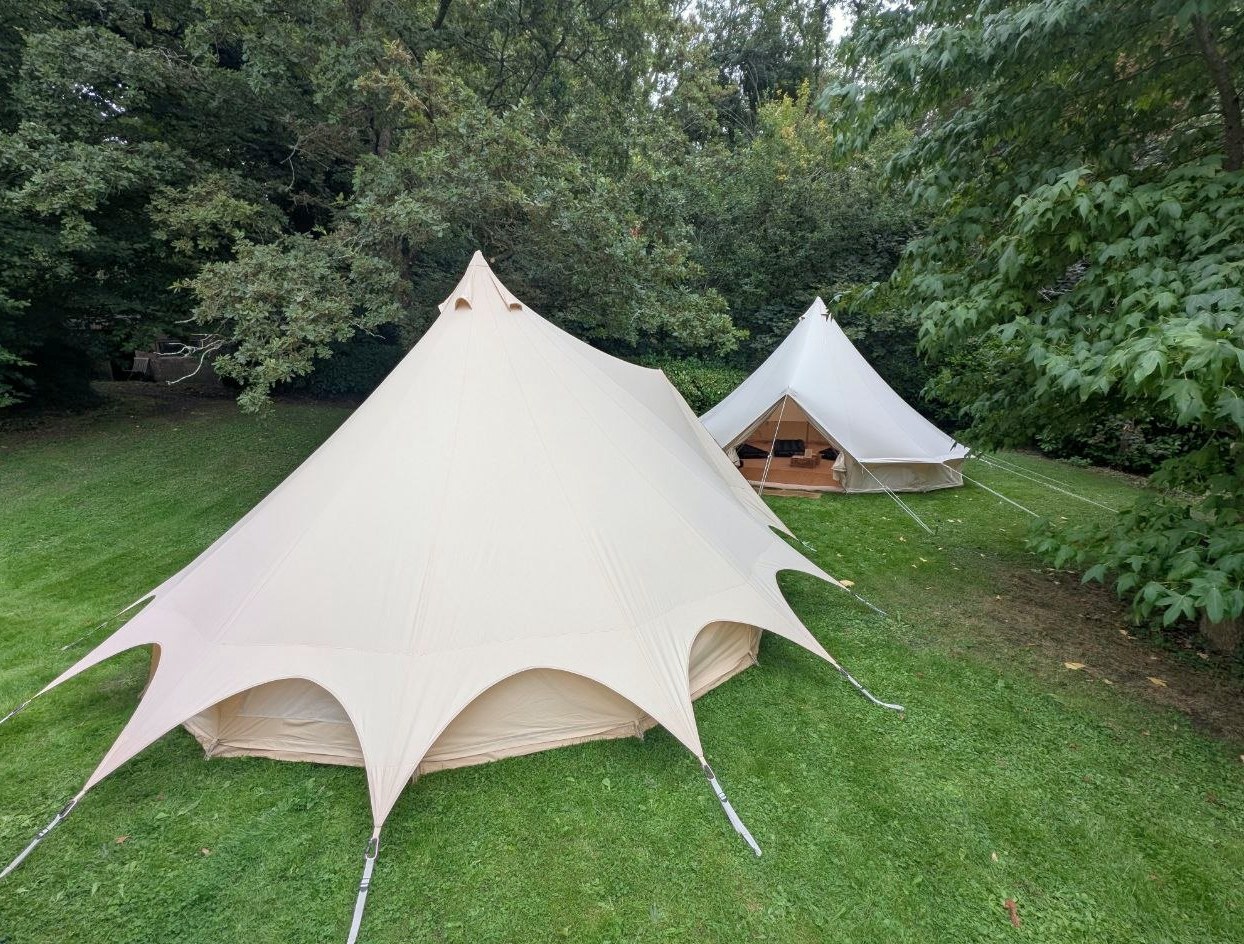 Two Camp Chic Rustic Bell tents nestled among mature trees in a private garden
