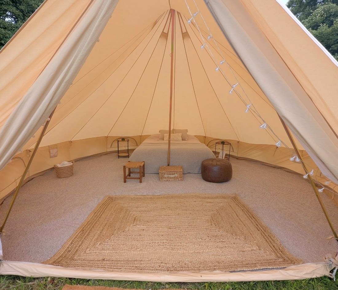 Furnished bell tent at Will’s Frome wedding with bed, rugs, bedside tables and warm canvas