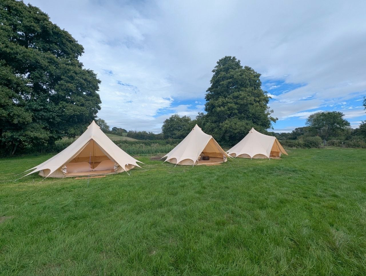 Three Camp Chic bell tents arranged on grass for Will’s wedding near Frome