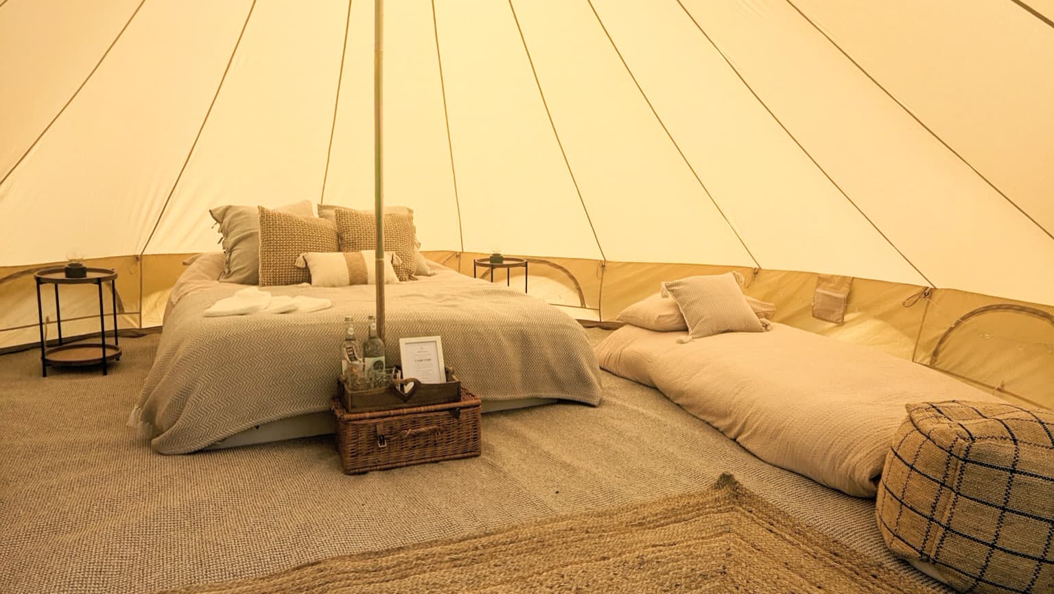 Styled Camp Chic bell tent interior with welcome tray, king bed and single air beds for family glamping