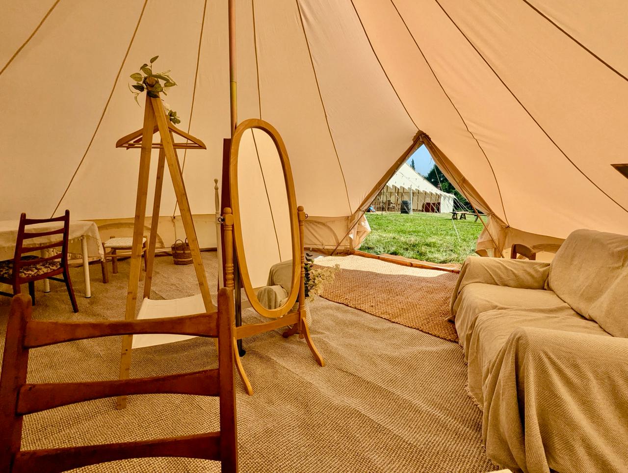 6m Camp Chic dressing tent with sofa, standing mirror, clothes rail and grass visible through the entrance for Ellie and Phil's Spargrove wedding