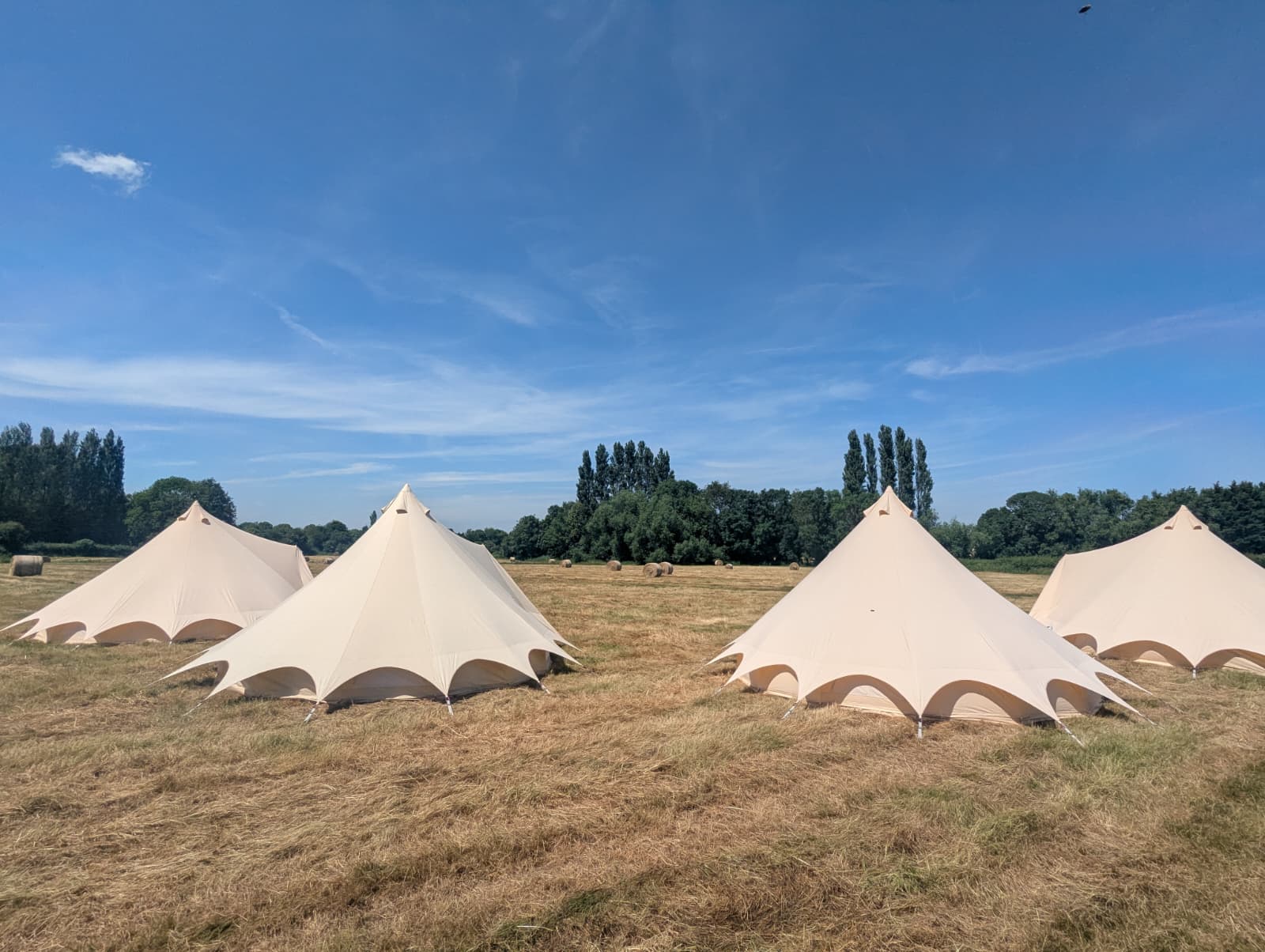 Camp Chic bell tents set up in a Bridgwater field under a blue sky for Georgia's wedding
