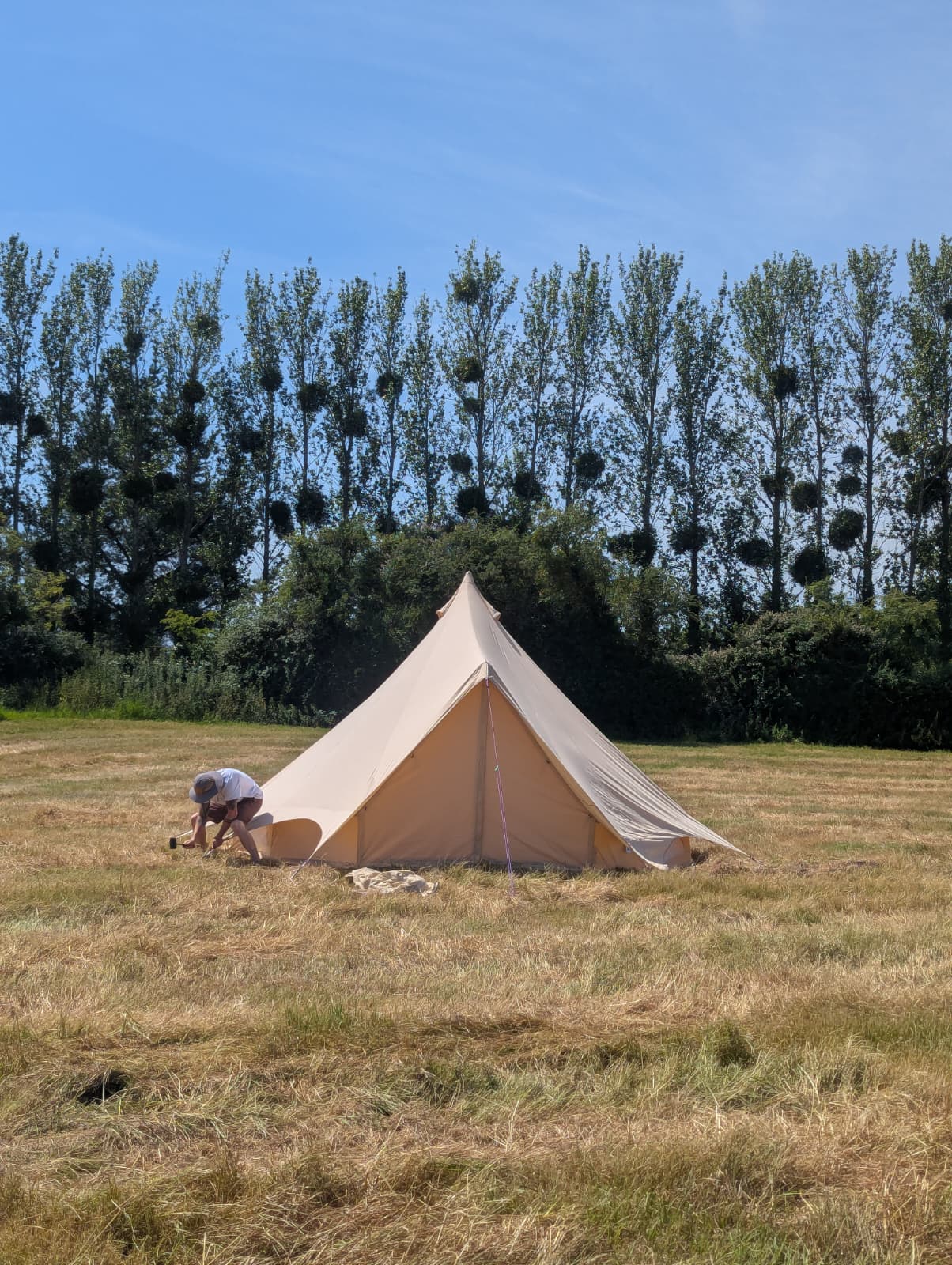 Camp Chic team setting up a bell tent in a field for Georgia's wedding in Bridgwater