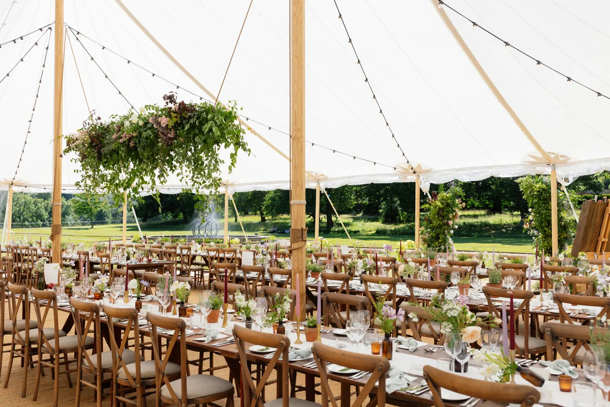 Rustic tables and cross-back chairs in a marquee