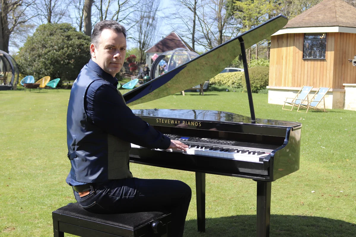 Pianist performing beside a garden pavilion