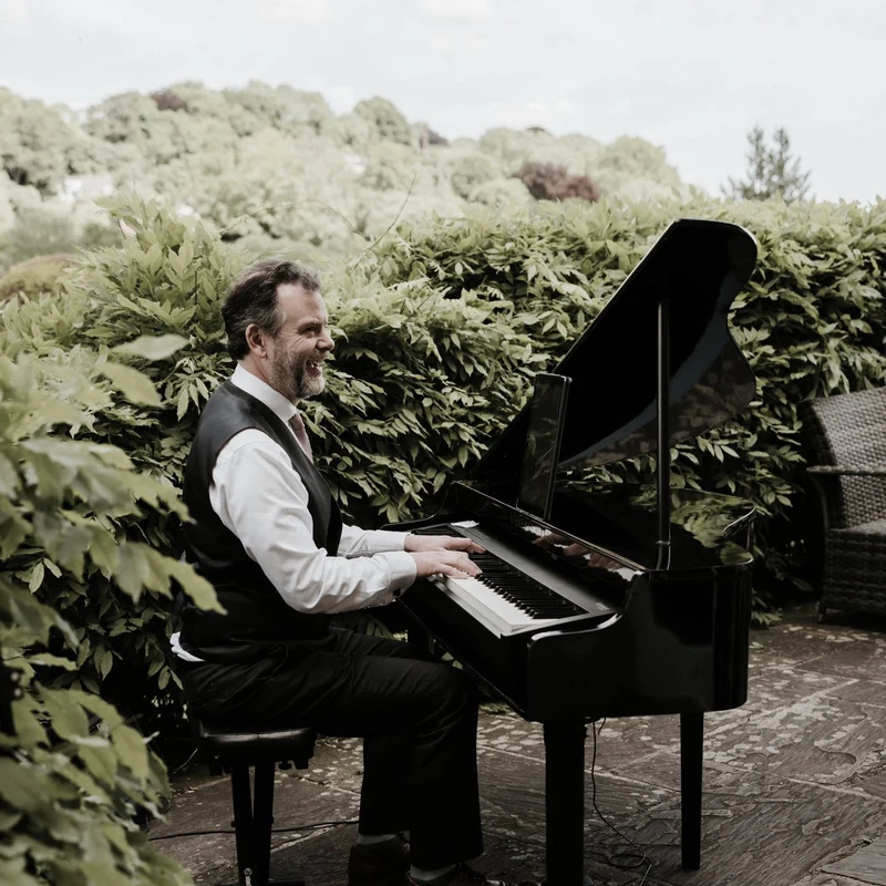 Matt Collins playing a piano outdoors